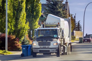 Calgary, Alberta, Kanada. 13 Ekim 2022. Bir çöp kamyonu yeşil bir araba yiyecek ve bahçe atığı alıyor..