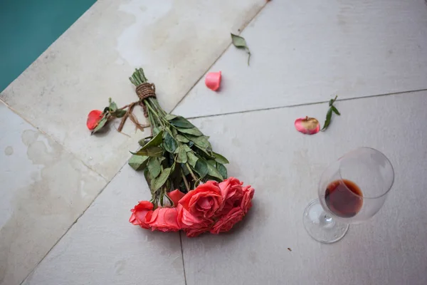 Κόκκινο μπουκέτο τριαντάφυλλα και ένα ποτήρι κόκκινο κρασί παραμένει — Φωτογραφία Αρχείου