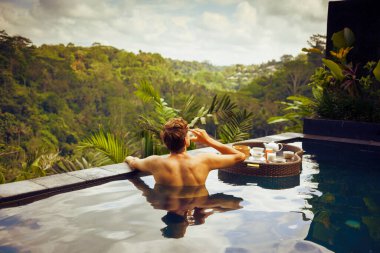 Meyve suyu içen adam yüzen tepsinin tadını çıkarıyor.