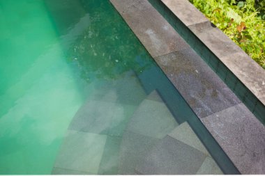 Yüzme havuzunun derin ve berrak sularına merdivenler