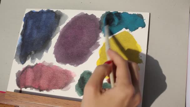 Змішування оксиду чорного акварелі в синій колір на папері — стокове відео