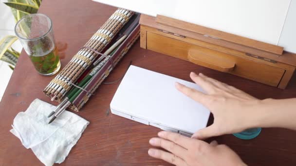 Hands opening plastic box of watercolor near easel — Stock Video