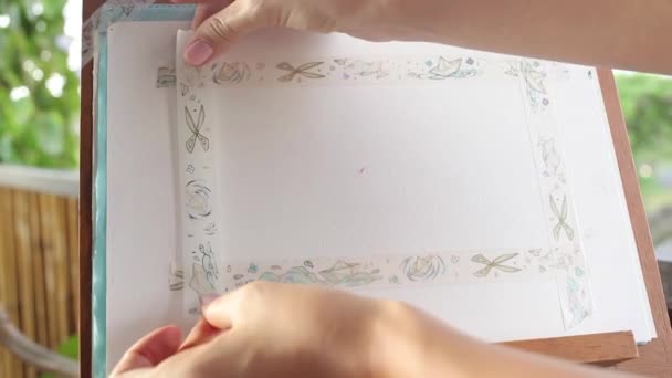 Girl sticking washi tape to paper creating frame — Stock Video