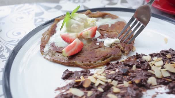 Girl eating sweet brown flour pancake with cream — Stock Video