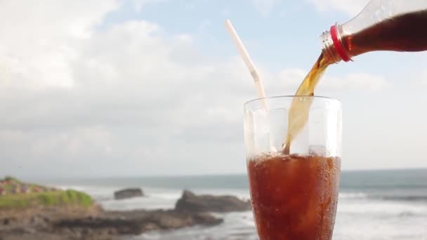 Pouring coke into glass with ice at ocean beach — Stock Video