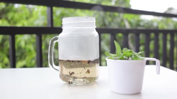 Pouring water in glass mug with tea and fresh mint — Stock Video