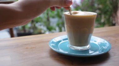 Kaşıkla latte karıştıran ve köpük yiyen kız.