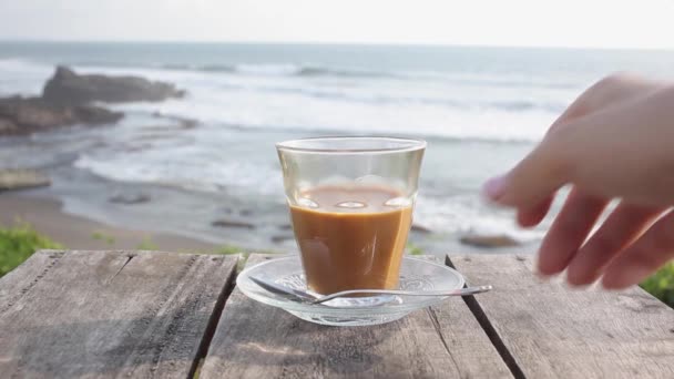 Dziewczyna mieszając latte na stole w kawiarni na plaży na zewnątrz — Wideo stockowe