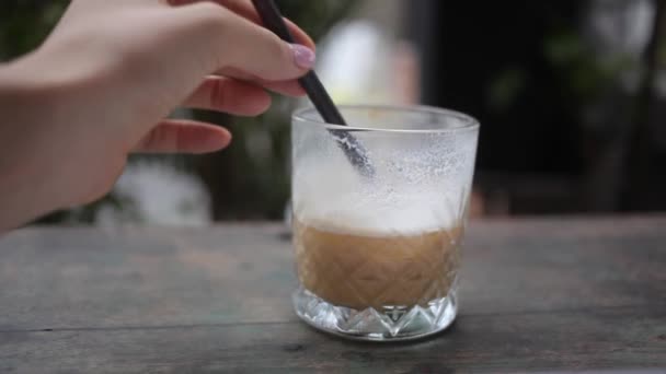 Vrouwelijke hand die suiker roert en ijskoffie drinkt — Stockvideo