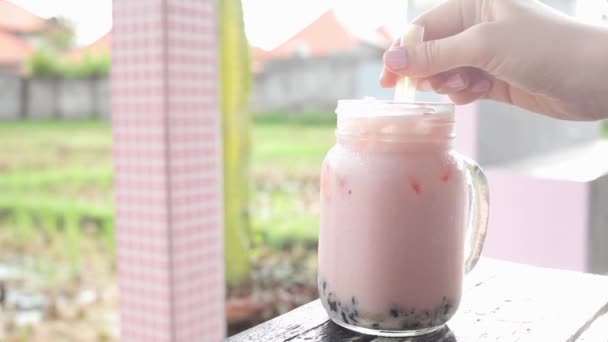 Meisje roeren roze boba met ijskoude drank in cafe — Stockvideo