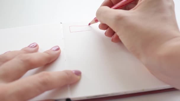 Meisje kijken rode kleur potlood op schetsboek pagina — Stockvideo