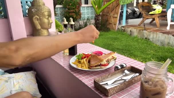 Hombre comiendo papas fritas en un café étnico en Bali — Vídeos de Stock