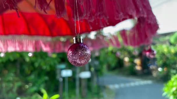 Блестящий розовый рождественский декор, качающийся на солнечном зонтике — стоковое видео