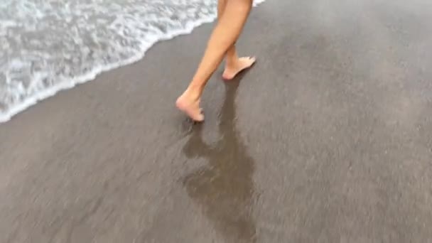 Cestovatel kráčející podél oceánu hřeben s šedým pískem — Stock video