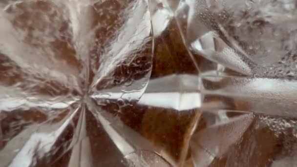 Macro-ijsblokjes drijvend in citroenwater in glas — Stockvideo