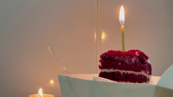 暗いインテリアで燃えるキャンドルと赤いベルベットの誕生日ケーキ。白いタイル張りの部屋でB日パーティーでケーキのピース. — ストック動画