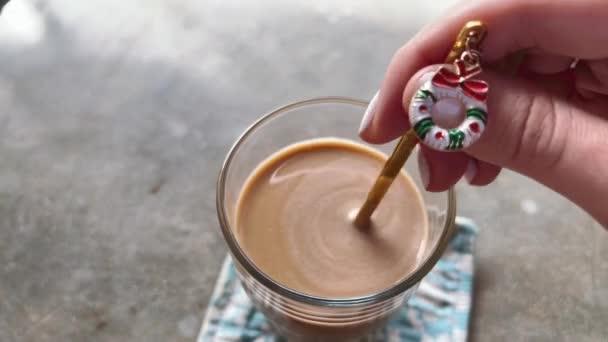 Χριστουγεννιάτικο στεφάνι ως διακόσμηση κουτάλι για καφέ ποτό σε τραπέζι γυαλισμένο σκυρόδεμα. Yum latte σε ένα ποτήρι το πρωί των Χριστουγέννων. — Αρχείο Βίντεο