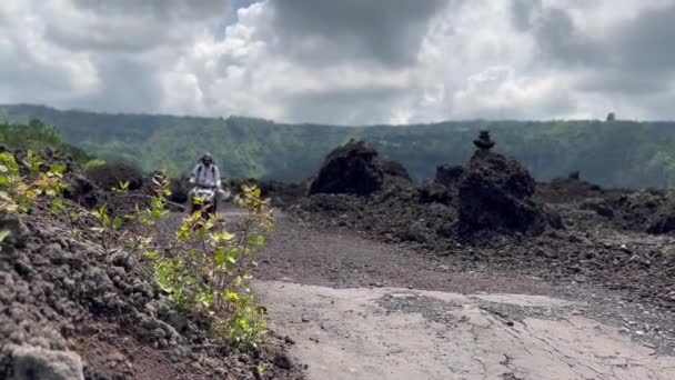 Kintamani Bali Indonesia - 9 de dezembro de 2021: homem andando de moto em lava preta em Kitamani Bali. Viajante masculino dirigindo ao longo da pista de montanha. — Vídeo de Stock