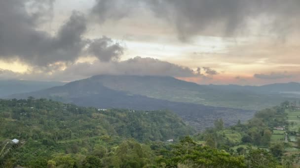 Prachtige Batur vulkaan en meer onder stromend wolken op Bali eiland in Indonesië. Natuurgroene vallei en mistige bergen op gouden uur in de zomer. — Stockvideo