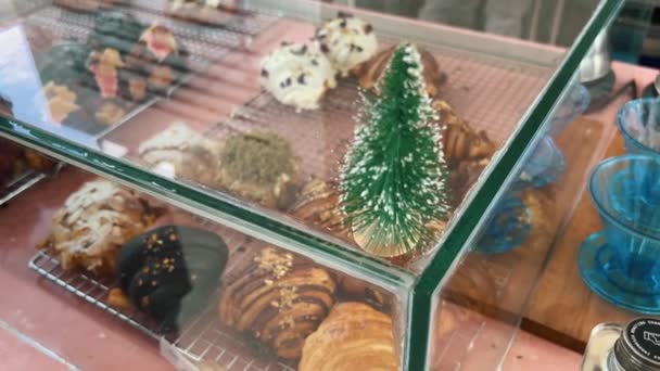 Niedlicher kleiner Weihnachtsbaum auf einem Fenster mit Brötchen. Yum Bäckerei in einem Café an Heiligabend. Christlicher Morgengenuss. — Stockvideo