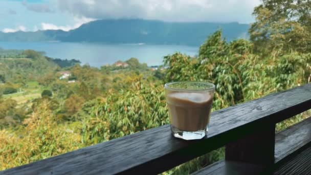 Koffie latte glas op rail boven groene vallei in de bergen. Goede morgen. Cafeïne drank in Bali - AmarillasLatinas.net. — Stockvideo