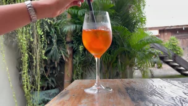Meisje roeren aperol spritz cocktail en drinken. Heerlijke alcoholische drank met citrusvruchten in een zomerbar. — Stockvideo