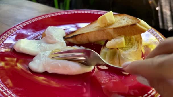 El corte casero hizo huevos escalfados con tostadas y mantequilla en el plato rojo. Desayuno rústico al aire libre. — Vídeo de stock