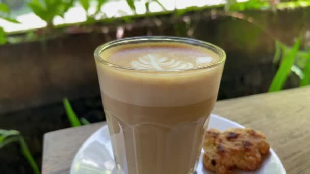Girl dipping biscuit into thick foam with latte art of delicious hot coffee — 图库视频影像