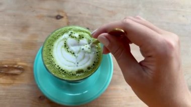 Sütlü sütlü sütlü çay karıştıran bir kadın..