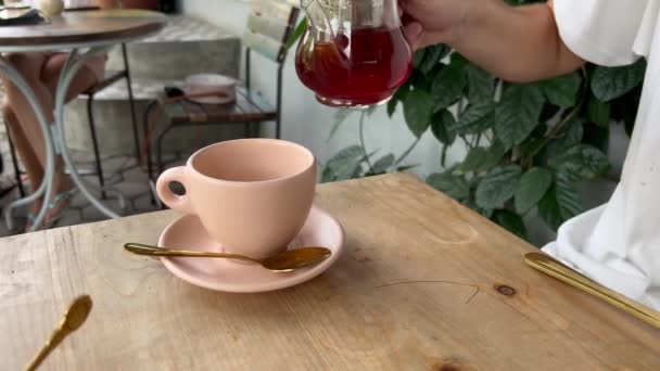 Man pouring black tea into pink cup at cafe outdoors. Good morning. Tea time for anonymous male person — Vídeo de Stock