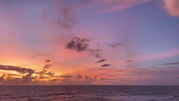 Удивительный розовый и фиолетовый закат над океанскими волнами. Драматическое небо в сумерках на острове Бали. — стоковое видео