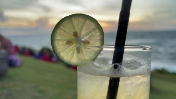 Delicious lime juice and vodka alcoholic cocktail on a beach at seaside. Stirring tropical mojito with ice. — Stockvideo