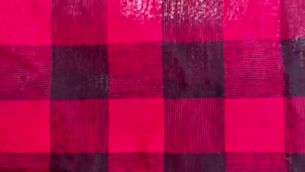 Rotes und schwarz kariertes Tuch, das sich im Freien windet. Defokussiertes Makro- und fernes Baumwollgewebe. Weihnachtlicher Hintergrund. — Stockvideo