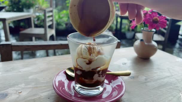 Delicious affogato coffee at street cafe in summer. Pouring espresso coffee on ice cream scoops in a glass. — 图库视频影像