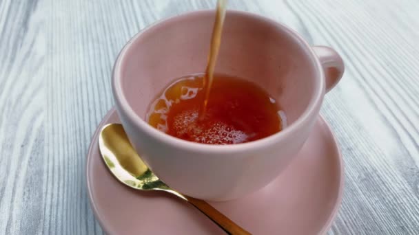 POV pouring black tea into a pink mug on a white wooden table at cafe. — Vídeos de Stock