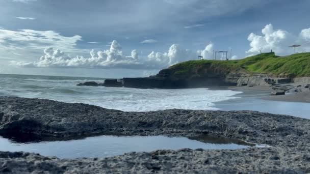 검은 모래사장에서 암초와 푸른 나무와 충돌하는 바 다 물결 이 아름다운 풍경을 이루고 있다. 열 대의 섬 풍경. — 비디오