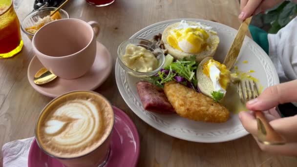 Eggs benedict for a hungry man. Breakfast with poached eggs, hashbrown, vegetables and latte coffee at cafe. — 비디오