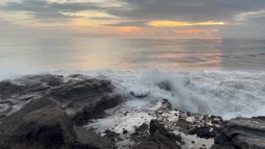 Powerful waves splashing on dark rocks at sunset. Ocean tide at dusk. Amazing dramatic landscape. Natural energy.