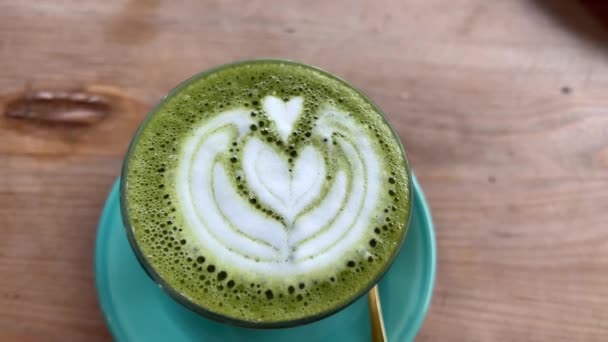 Close-up macrobeelden van groene thee matcha latte met latte art. Heerlijk melkachtig drankje op tafel. Bovenaanzicht. — Stockvideo
