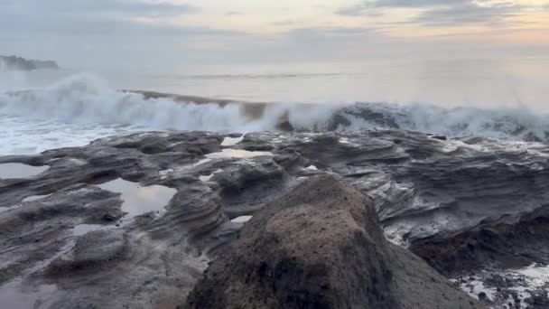 Een enorme plons water die op donkere rotsen valt op het gouden uur op een prachtig wild strand. Krachtige vloedgolven die het zwarte stenen rif raken. Geweldige kracht van de natuur. Oceaan kust zonsondergang scène. — Stockvideo