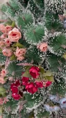 Sahte çiçeklerle süslenmiş güzel bir Noel ağacı. Yapay güller köknar ağacındaki yeni yıl süsleridir. Xmas arifesinde lüks bir yaşam tarzı.