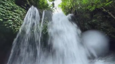 POV görüntüsü, vahşi doğadaki tropikal şelalenin dengesiz canlı kamera görüntüleri. Orman yağmur ormanı nehir taşkını. Endonezya 'yı keşfedin. Nehir yüzeyine devasa bir su akışı düşüyor..