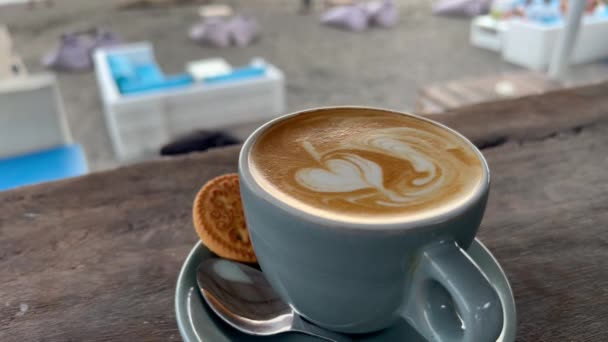 Latte coffe i en grå kopp på en träbar på strandcaféet. Njut av en stormig dag med stark vind dricka koffein. — Stockvideo