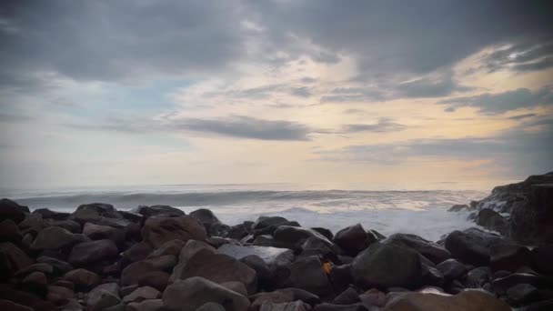 Красиві живі камери перегляд потужних океанічних хвиль, які б'ють чорними каменями зі свіжими бризками на заході сонця . — стокове відео