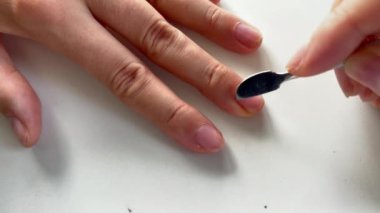 Evde manikür yapıyor. Beyaz arkaplandaki tırnaklara tırnak eti batırmak için el temizleyicisi kullanırken çekilmiş yakın çekim görüntüleri..