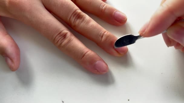 Faire des manucures à la maison. Gros plan de la main à l'aide d'un poussoir à cuticules pour pousser la cuticule sur les ongles sur fond blanc. — Video