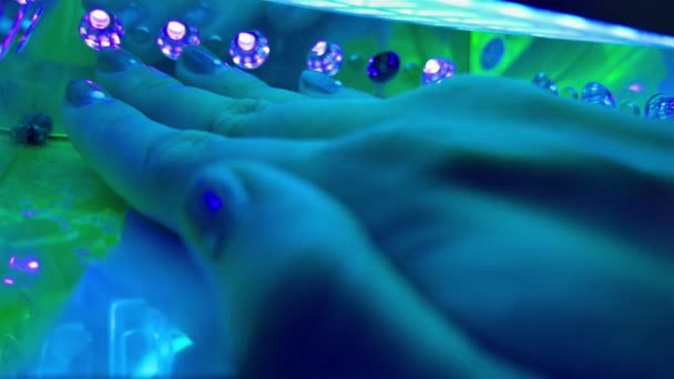 Suszarka UV LED Suszarka żel lakier do paznokci niebieski neon ultrafioletowe światło. zielone i niebieskie światło lampy manicure z nieostrą ręką na pierwszym planie. — Wideo stockowe