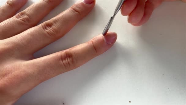 POV poussant la cuticule sur les ongles à l'aide d'un poussoir à cuticule métallique. Procédure SPA sur fond blanc en lumière naturelle. — Video