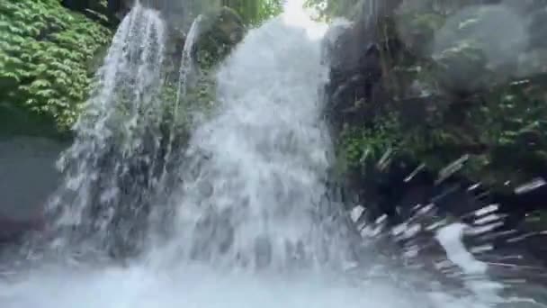 熱帯のジャングルの中の滝の美しいライブカメラ映像は、湖の表面に水滴が太陽の下で輝いて飛び散っています。熱帯雨林の冒険. — ストック動画