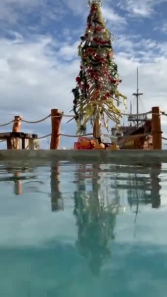 热带天堂游泳池边美丽的圣诞树 在印度尼西亚巴厘岛Melasti海滩的海滩俱乐部 圣诞树上有装饰品和礼物 高质量的胶片颗粒镜头 — 图库视频影像